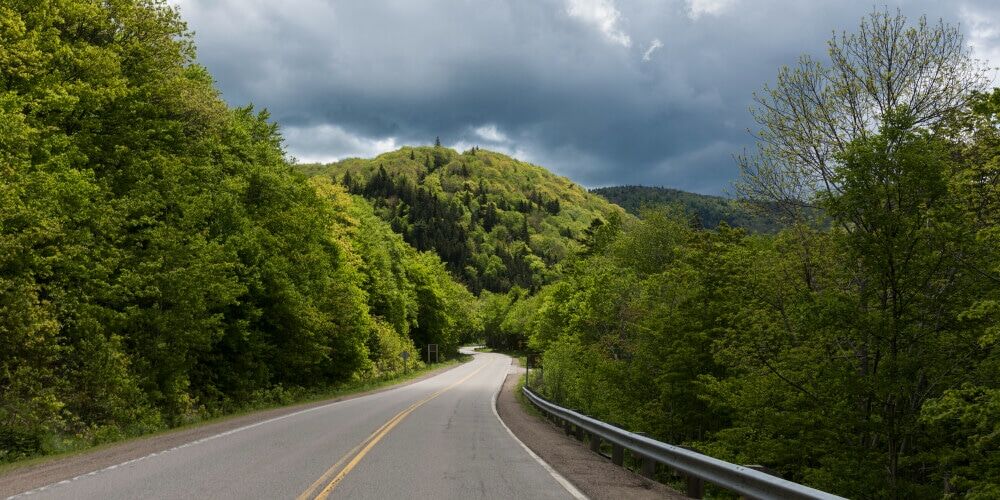 empty-road-amidst-trees-by-hills-pleasant-bay-cape-breton-highlands-national-park-cape-breton-isl (1)