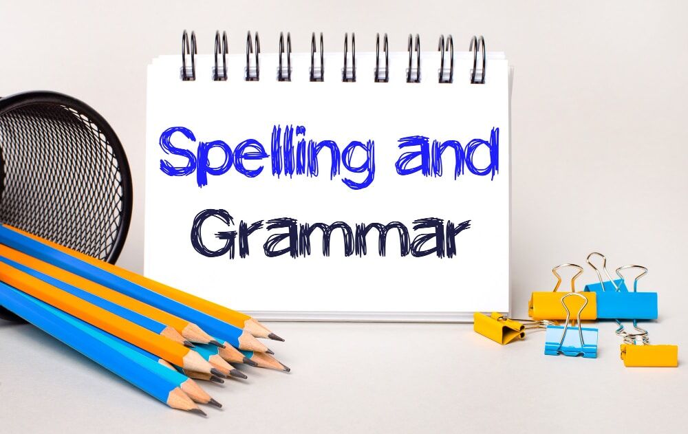 light-background-yellow-blue-pencils-paper-clips-white-notebook-with-text-spelling-grammar